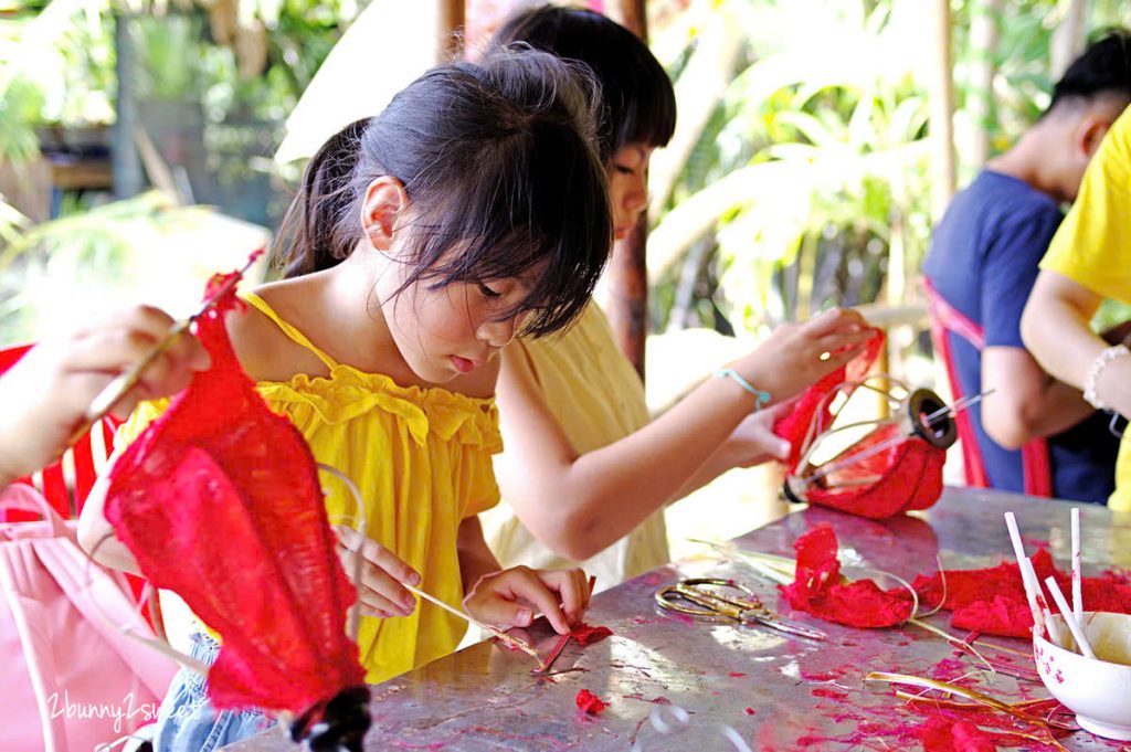 Bé gái đang buộc lạt tre trong lớp học làm đèn lồng Phú Quốc bên sông